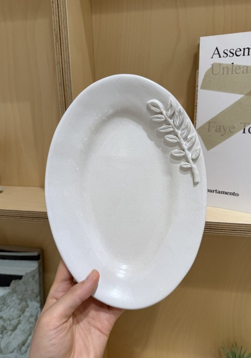잎사귀 가지 하나를 길게 눕힌 접시