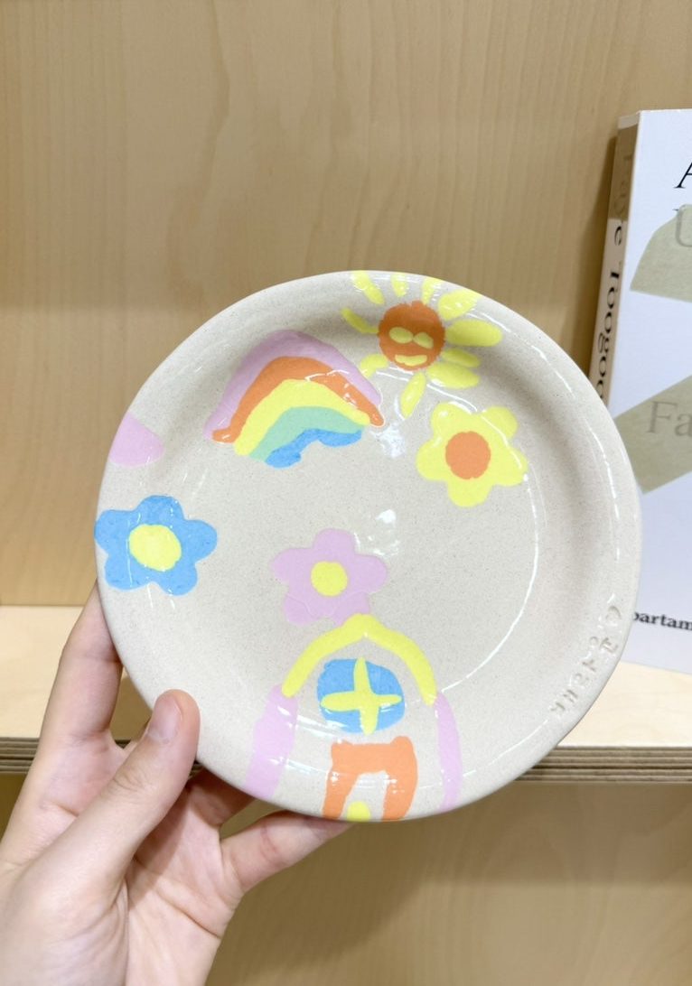 무지개와 꽃, 집 무늬를 넣어 구워 낸 완성 접시를 든 손